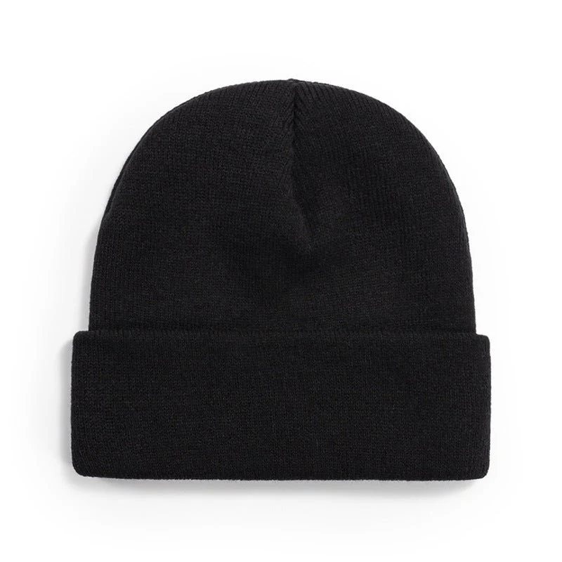 Black and white knit beanie on a concrete surface in winter light