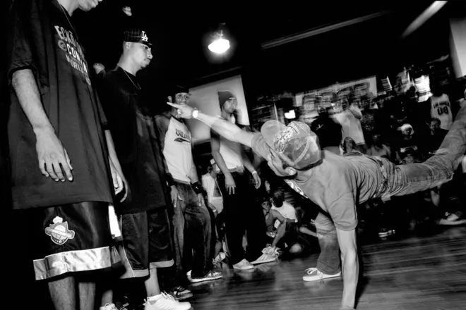 Rapper surrounded by a crowd under a bridge during a riverside cypher in Changsha