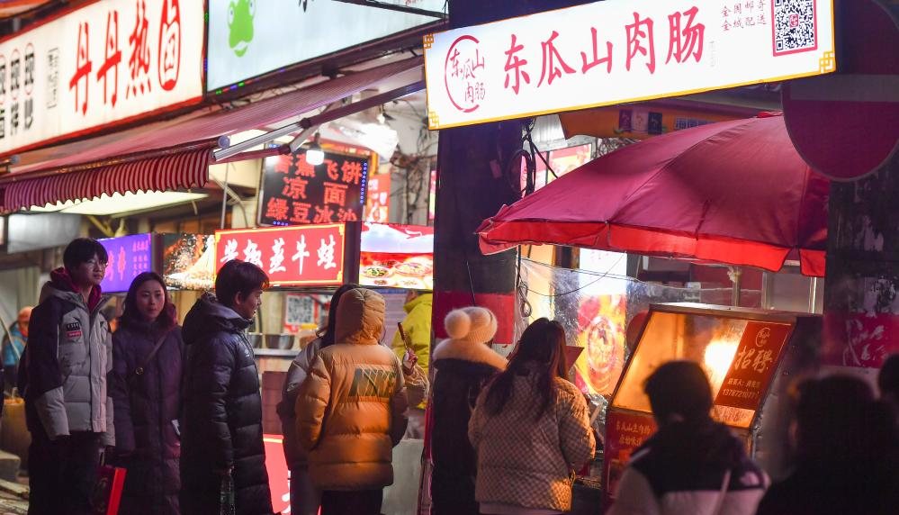 Bowls of spicy Hunan food and beer bottles on a night market table