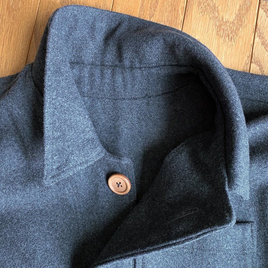 Black and white workwear jacket detail with heavy stitching and metal buttons