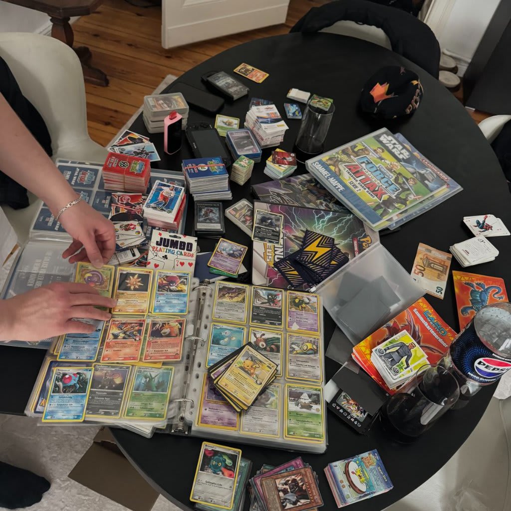 Cartes Pokémon holographiques rangées dans des toploaders rigides sur une surface en bois clair