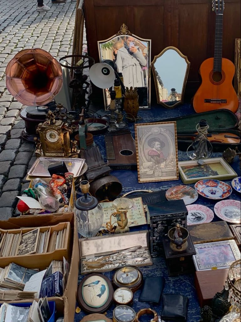Étal de brocante avec céramiques et mobilier vintage, marché en plein air, lumière du matin