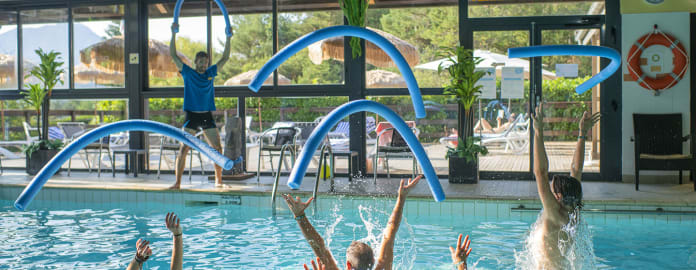 Cours d'aquagym dans une piscine intérieure, les participants lançant les frites en l'air - Club*** Les Horizons du lac - Chorges