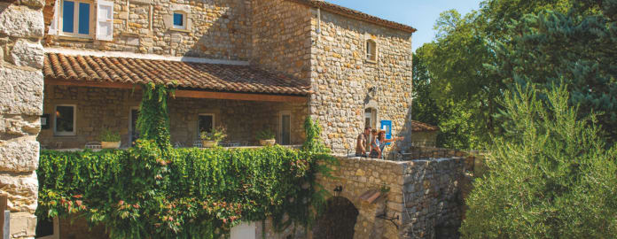 Vue de la terrasse extérieure en pierre au milieu des arbres avec une famille montrant du doigt l'horizon - Résidence 3 * Lou Castel - Ardèche