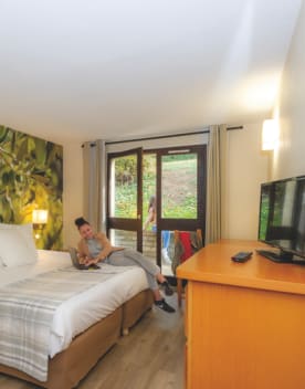 Chambre lit double avec jeune femme travaillant sur un ordinateur - Chateau Laval - Vacances Bleues