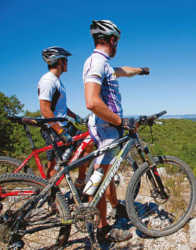 Deux hommes à coté de leur vtt en haut d'une colline regardant et montrant l'horizon du doigt - Résidence Lou Castel - Ardèche