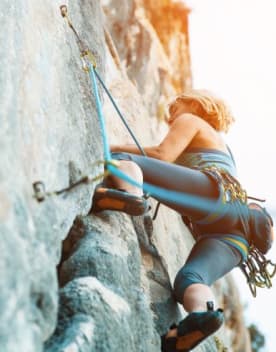 Escalade - Femme escaladant une paroi montagneuse
