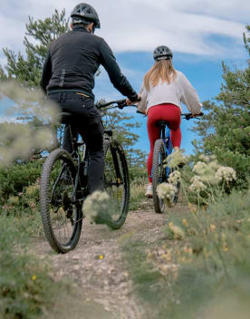 Couples de dos faisant une randonnée en VTT en montagne sous un ciel bleu - Club*** Les Horizons du lac - Chorges