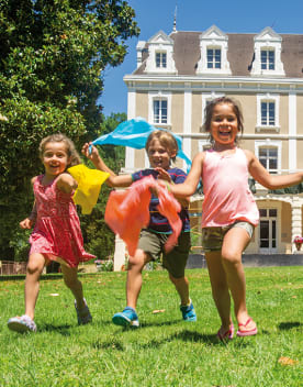 Enfants courant devant de château du domaine de Château Laval avec des foulards dans les mains - Club*** Château Laval - Gréoux les Bains
