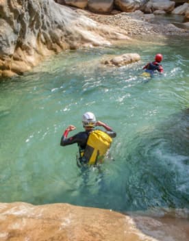Personnes dans la rivière transparente entre les gorges pratiquant le canyoning