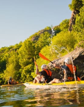 Canoë - Personnes pratiquant du canoë sur la rivière aux rives bordées d'arbres sous un ciel bleu