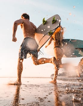 couple avec surf sur la plage - Le Sud-Ouest : des destinations entre charme et caractère