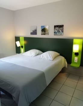 Chambre de l'établissement en gros plan le lit 2 personnes avec les lampes de chevet fixées au mur allumées et 3 cadres au dessus du lit - Résidence 3* Lou Castel - Ardèche