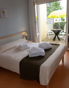 Chambre avec lit 2 personnes avec porte fenêtre ouverte sur une terrasse - Club*** Keravel - Erdeven
