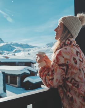 Femme de profil au balcon buvant un café face aux pistes - Eden des Cimes - Vacances Bleues