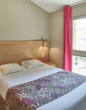 Appartement avec lit double oreillers et rideaux fushia - Chateau Laval - Vacances Bleues
