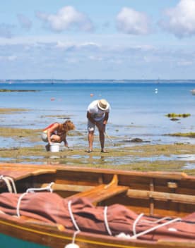 Deux personnes pratiquant la pêche à pied à marée basse en premier plan une barque en cale sèche - Club Keravel*** - Erdeven