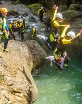 Canyoning - Groupe de personnes pratiquant le canyoning en rivière, en 1er plan deux personnes sautant dans l'eau depuis un rocher