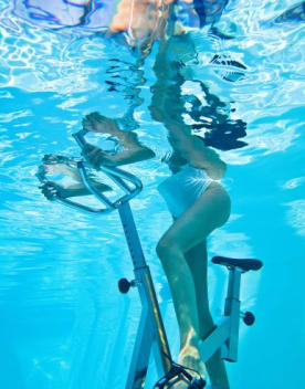 Vue sous l'eau d'une Femme sur un vélo pratiquant l'aquabike - Vacances Bleues