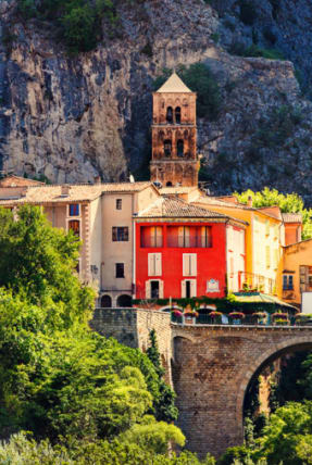 Village de Moustiers-Sainte-Marie au devantures colorées des maisons avec son pont en pierre sur la falaise - Club*** Château Laval - Gréoux les Bains