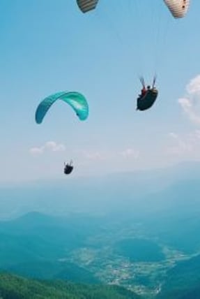 Personnes en parapente au dessus des sommets montagneux verdoyant