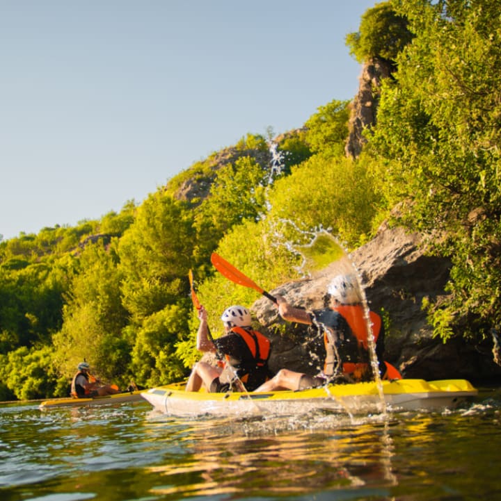 Personnes pratiquant du canoë sur la rivière bordée d'arbres sous un ciel