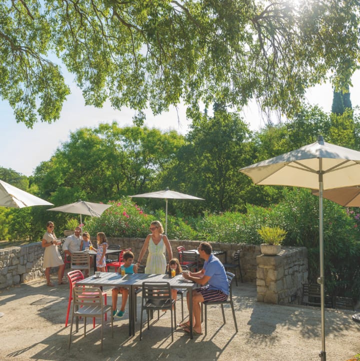 Famille attablée à la terrasse extérieure sous un arbre - Résidence 3* Lou castel - Ardèche