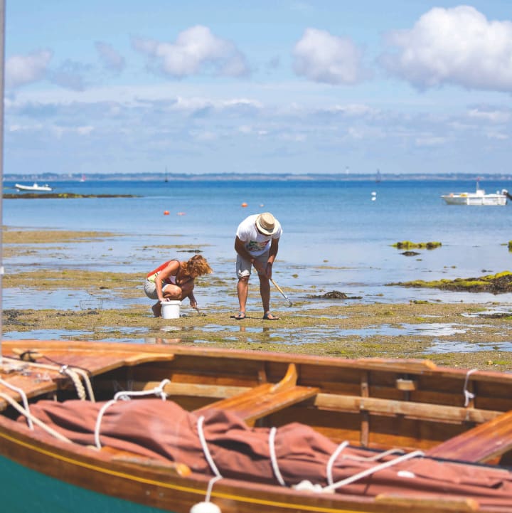 Deux personnes pratiquant la pêche à pied à marée basse en premier plan une barque en cale sèche - Club Keravel*** - Erdeven