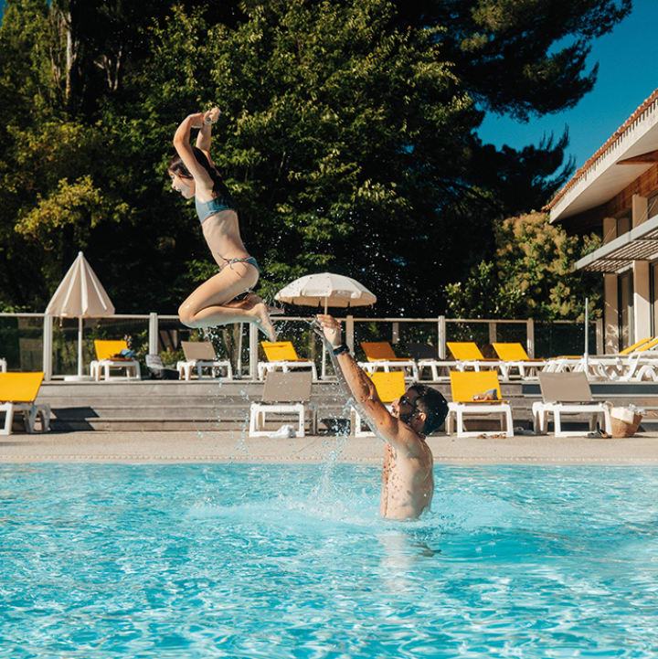 Un père faisant sauter sa fille dans la piscine extérieure - Club*** Château Laval - Gréoux les bains