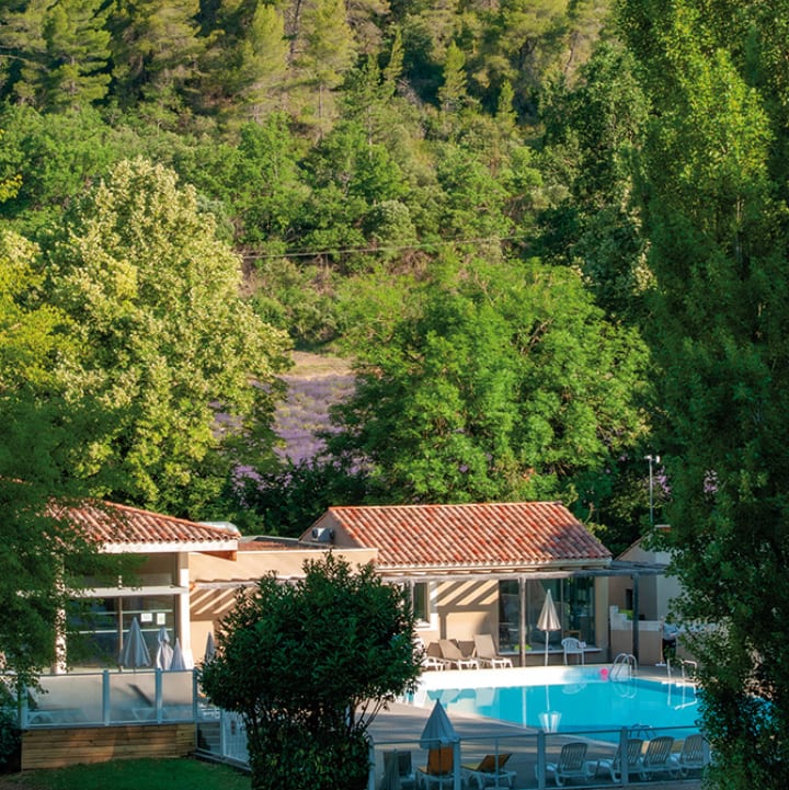 Vue de la piscine extérieure avec en arrière plan un champ de lavande - Club*** Château Laval - Gréoux les Bains
