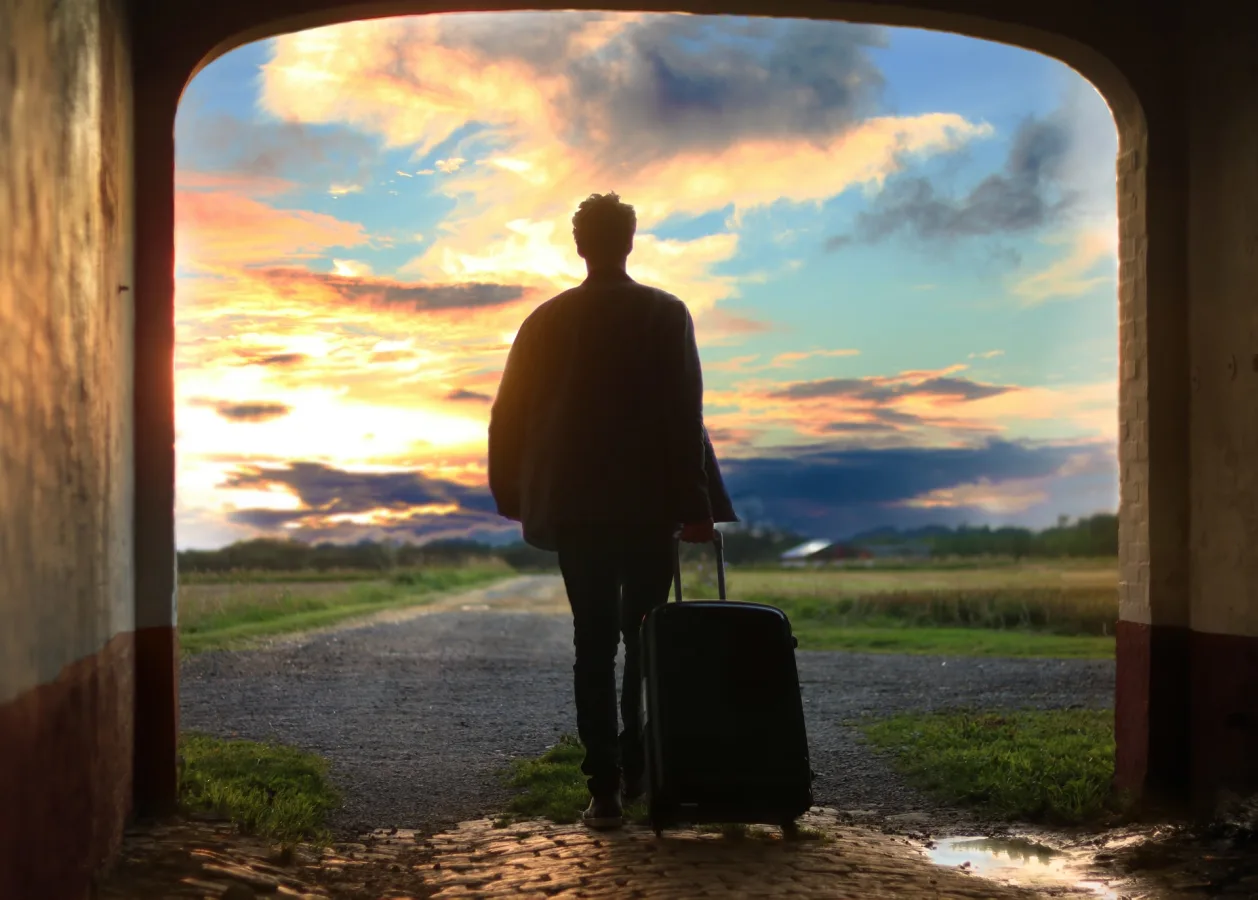 mental wellness benefits of travel man with suitcase walking toward future