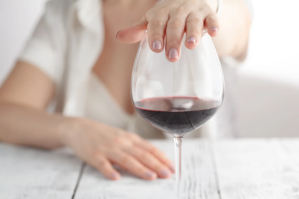 woman refusing glass of red wine essential wellness trend