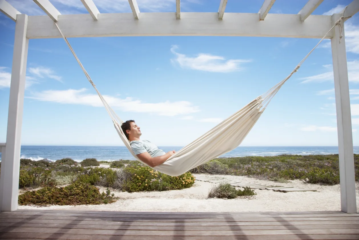 man sleeping in hammock on beach