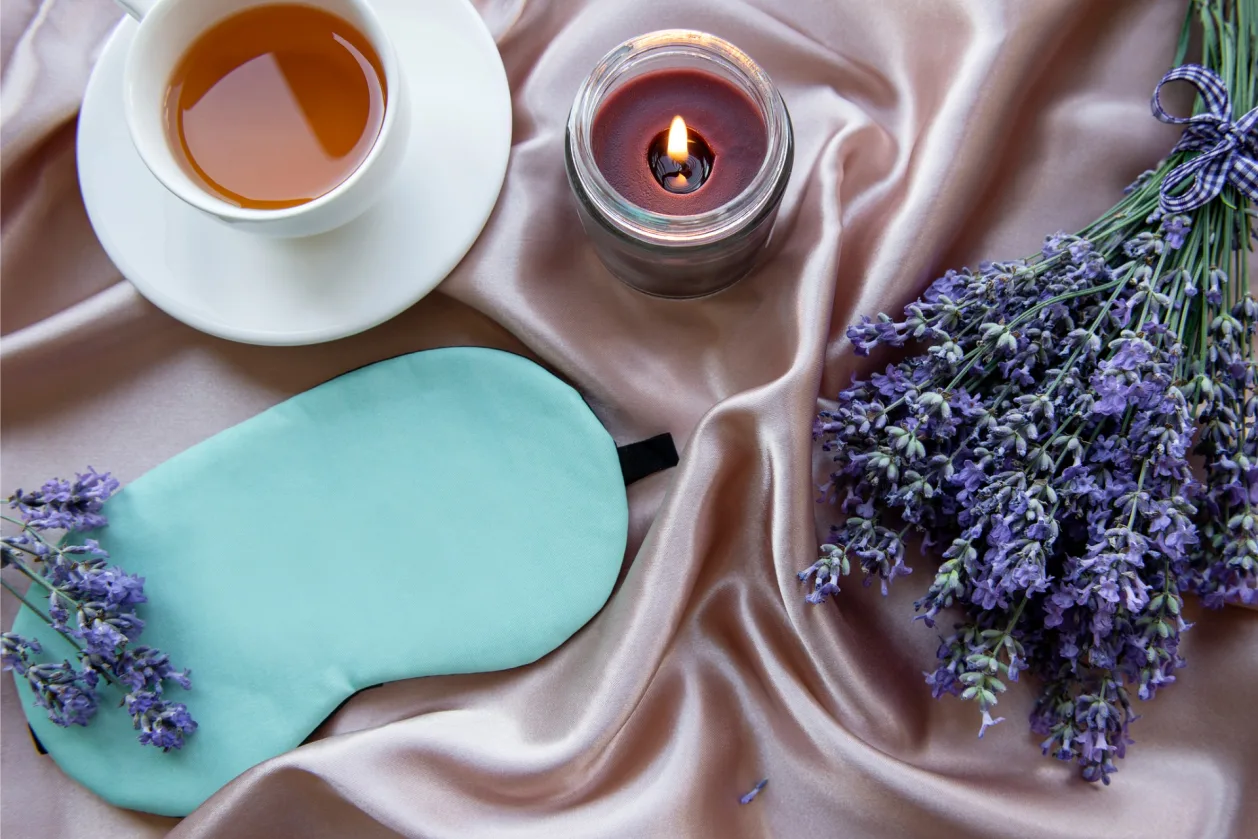 healthy sleep concept eye mask, lavender, tea, candle on sheet