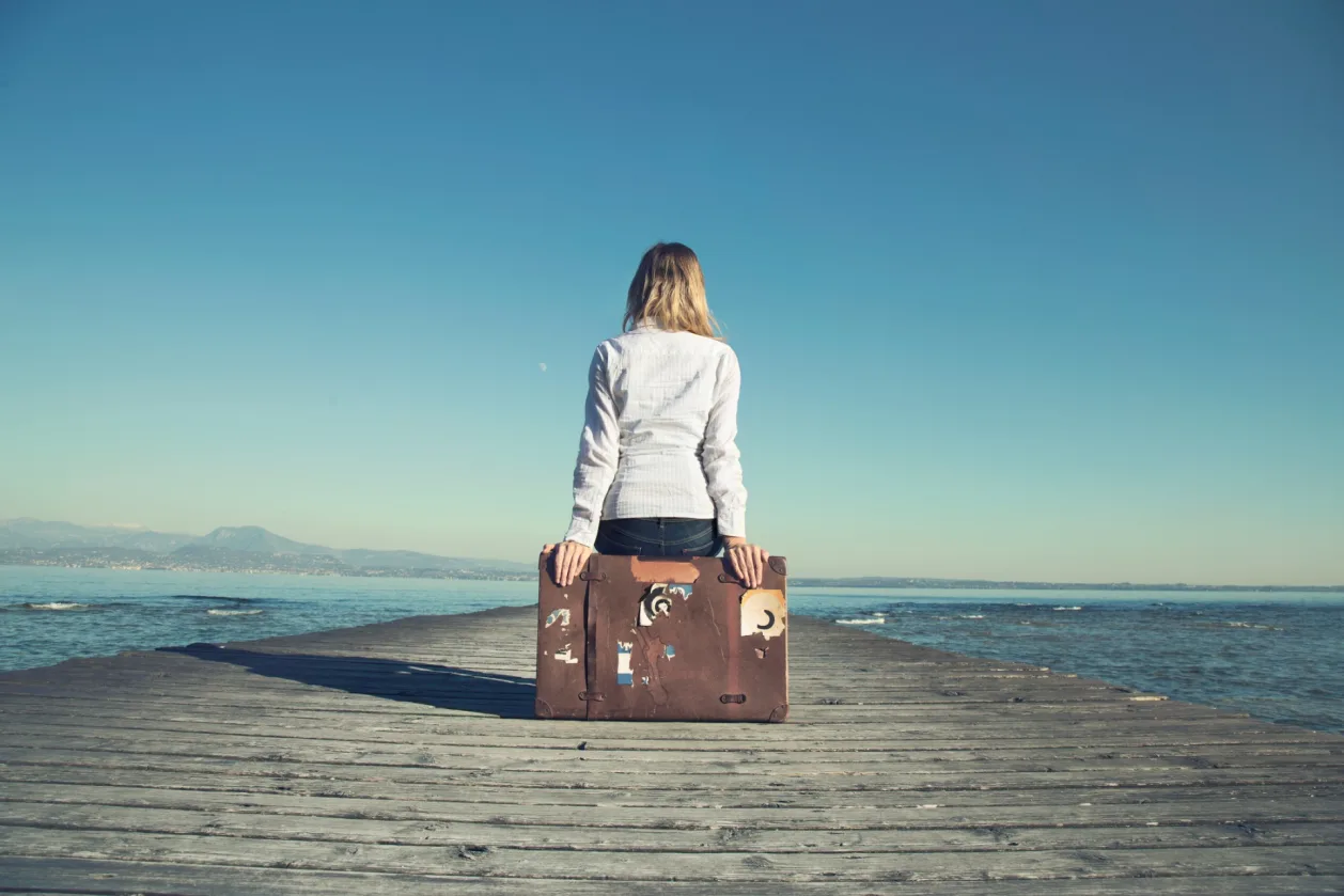 woman sitting on suitcase with travel anxiety