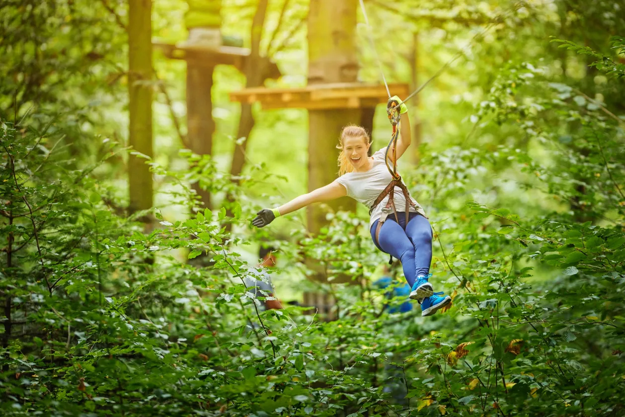woman ziplining in forest adult summer camp activity