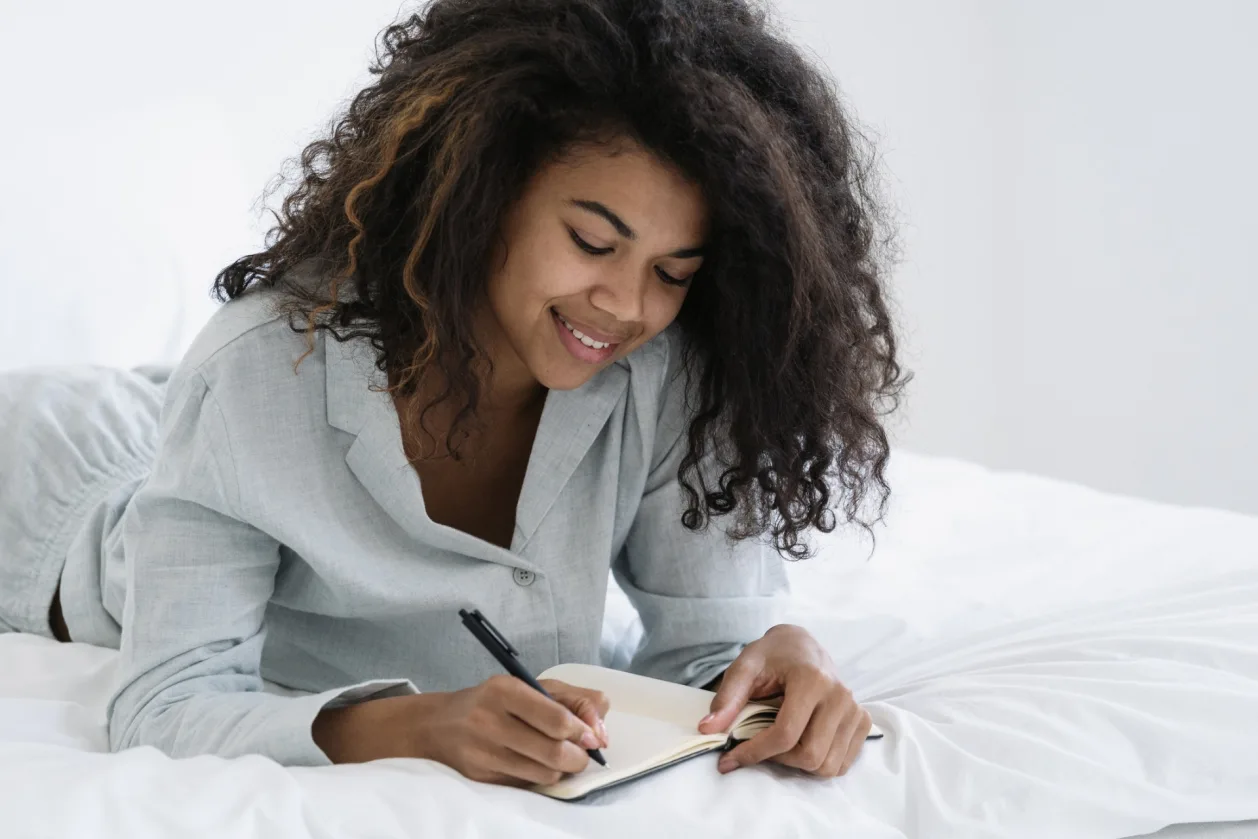 african american woman writes in journal as she winds down before bed