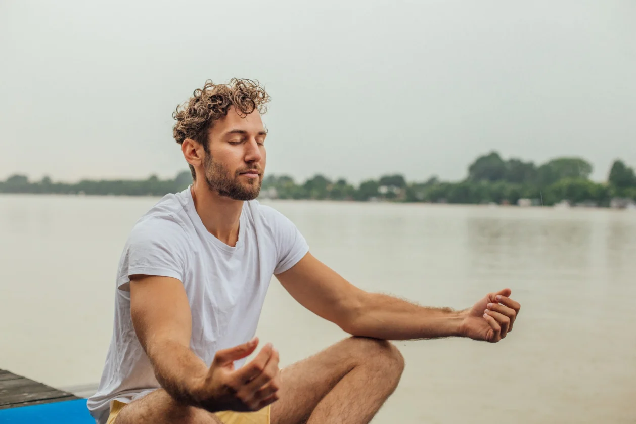 man meditating on dock
