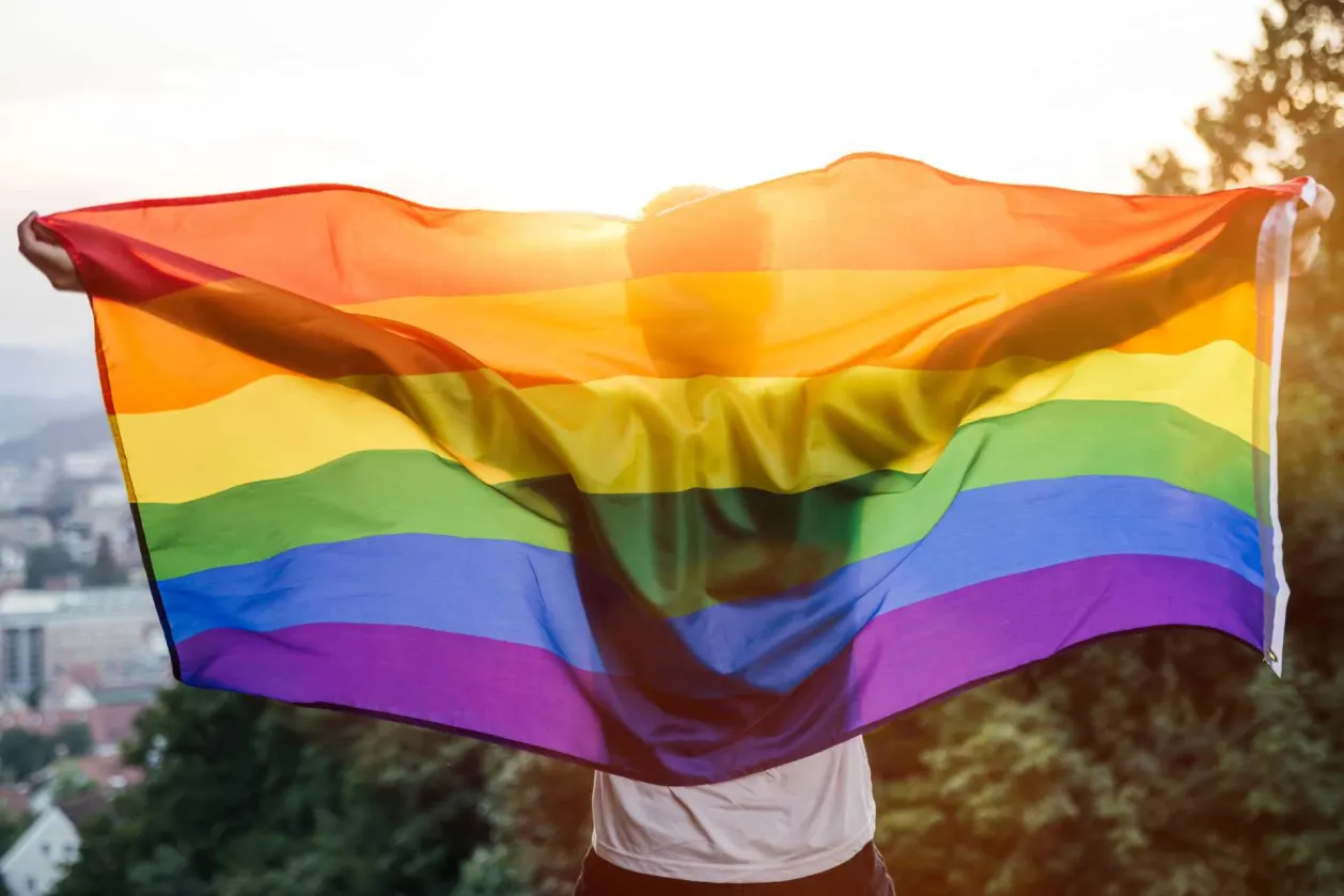 man holding pride flag LGBT friendly travel concept