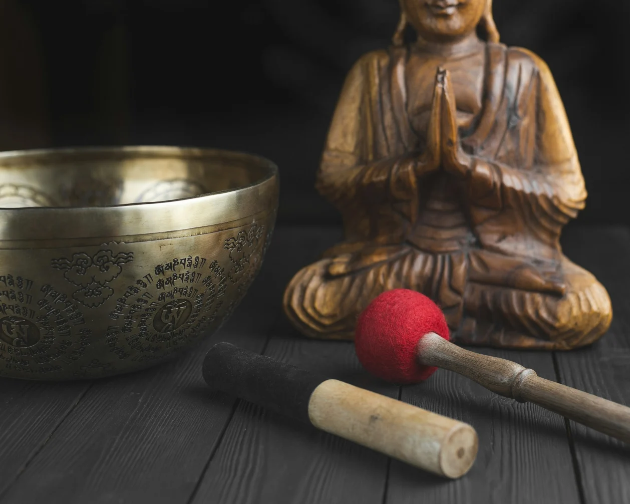 Tools for mantra meditation - tibetan singing bowl, sticks, statue of buddha. Translation text on bowl om mani padme hum