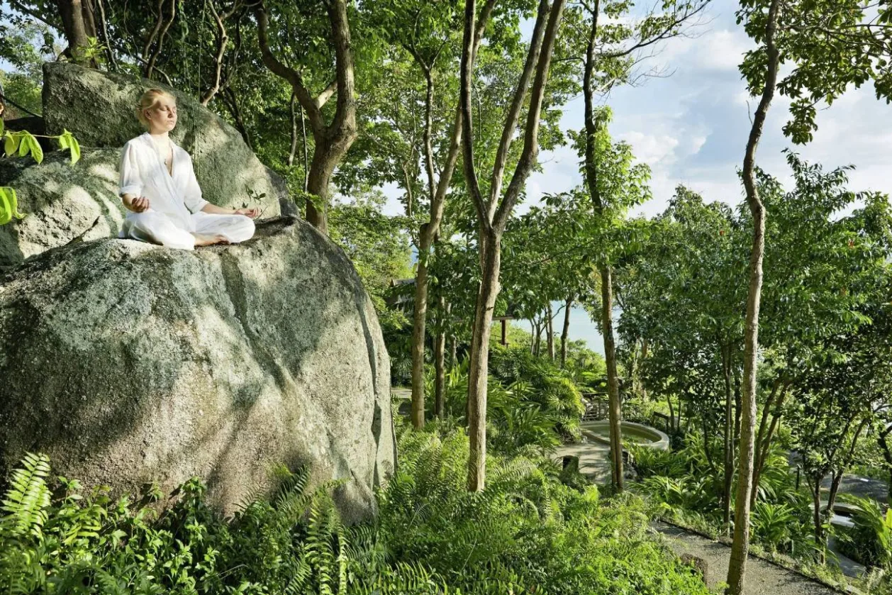 Woman meditating on rock at Kamalaya