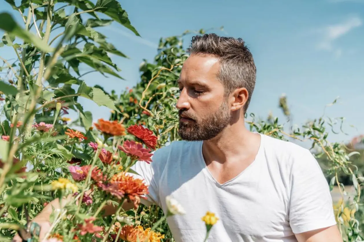Bearded man smelling flowers