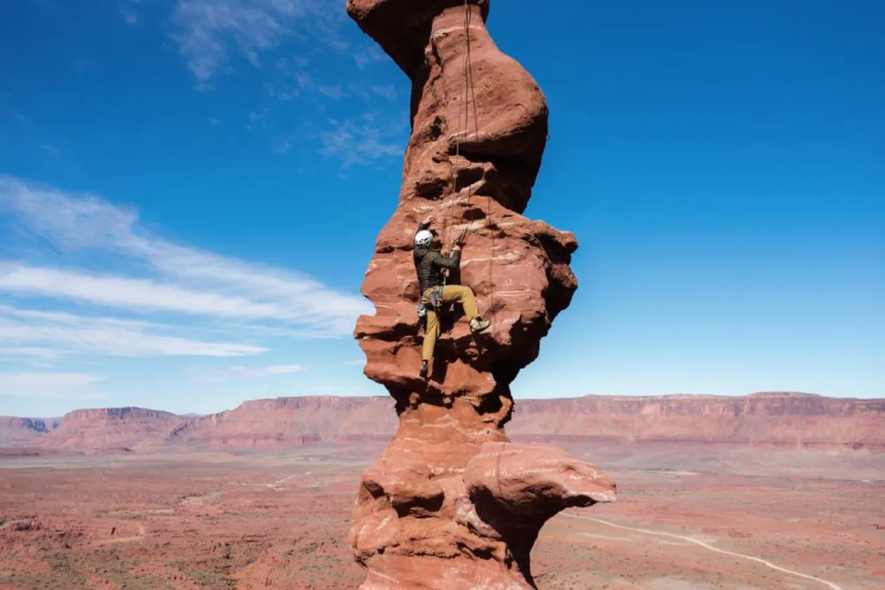 Rock climber ascending Stolen Chimney on Fisher Towers