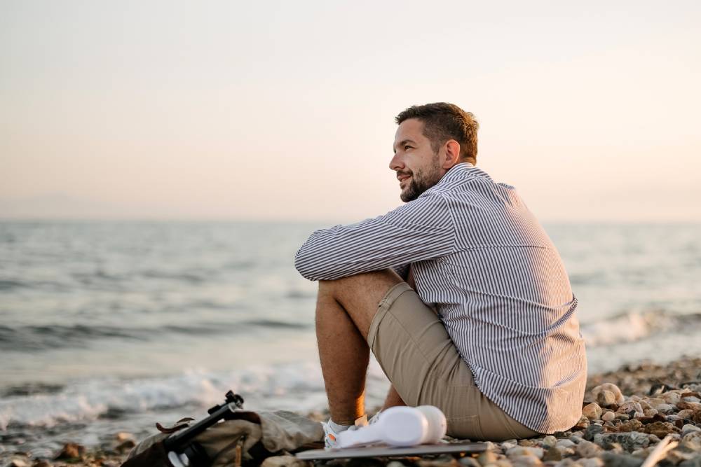 Man sitting quietly on rocky beach