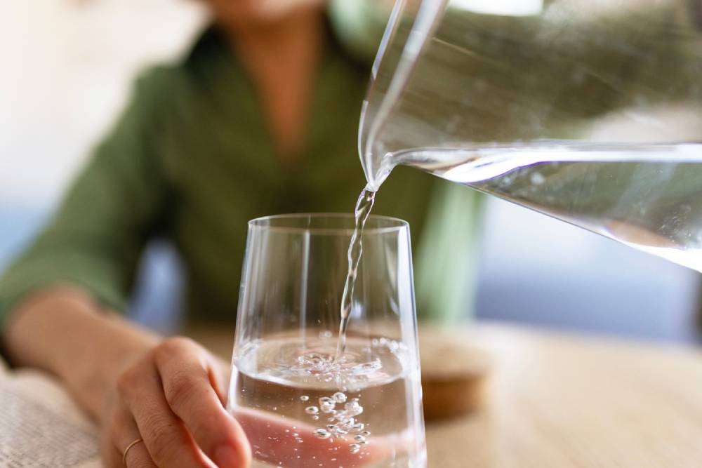 Close up of woman pouring water from carafe into glass