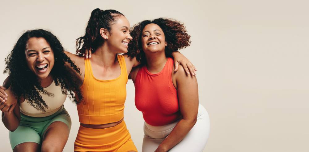 Three female friends laughing in sports clothing