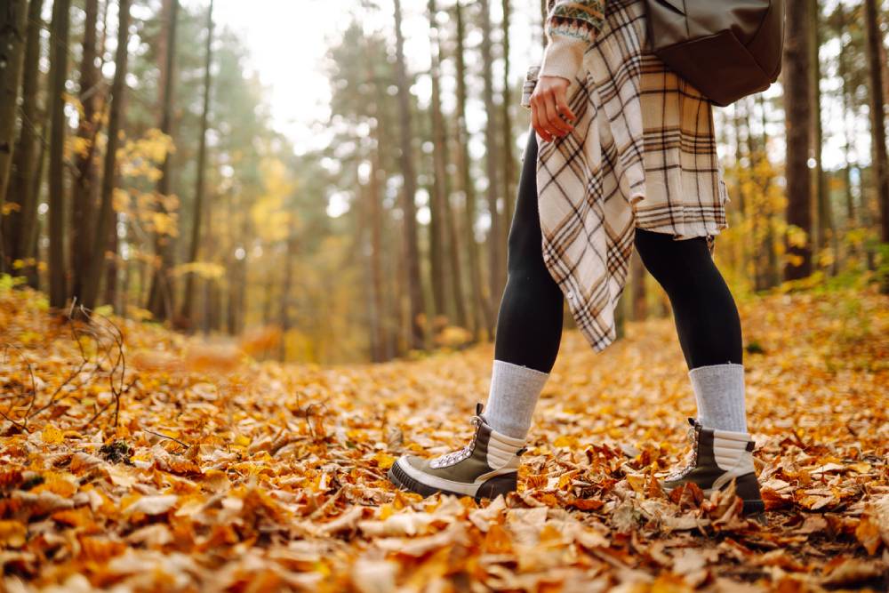 Woman's legs in boots in autumn foliage