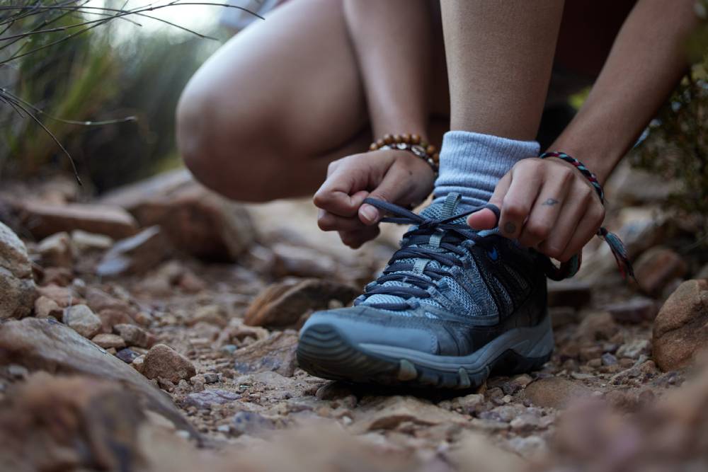 Cropped shot of an unrecognizable woman tying her laces while out hiking