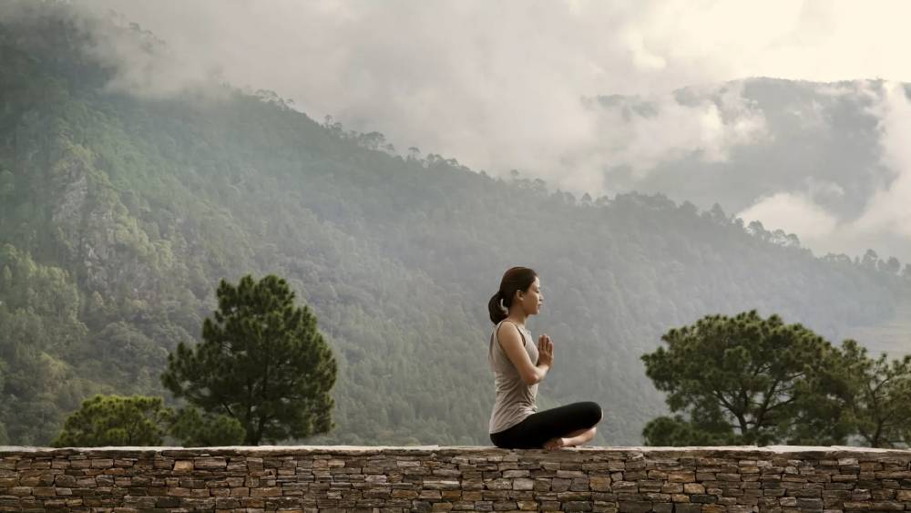 Woman meditating on fence at COMO Shambhala Uma Punakha