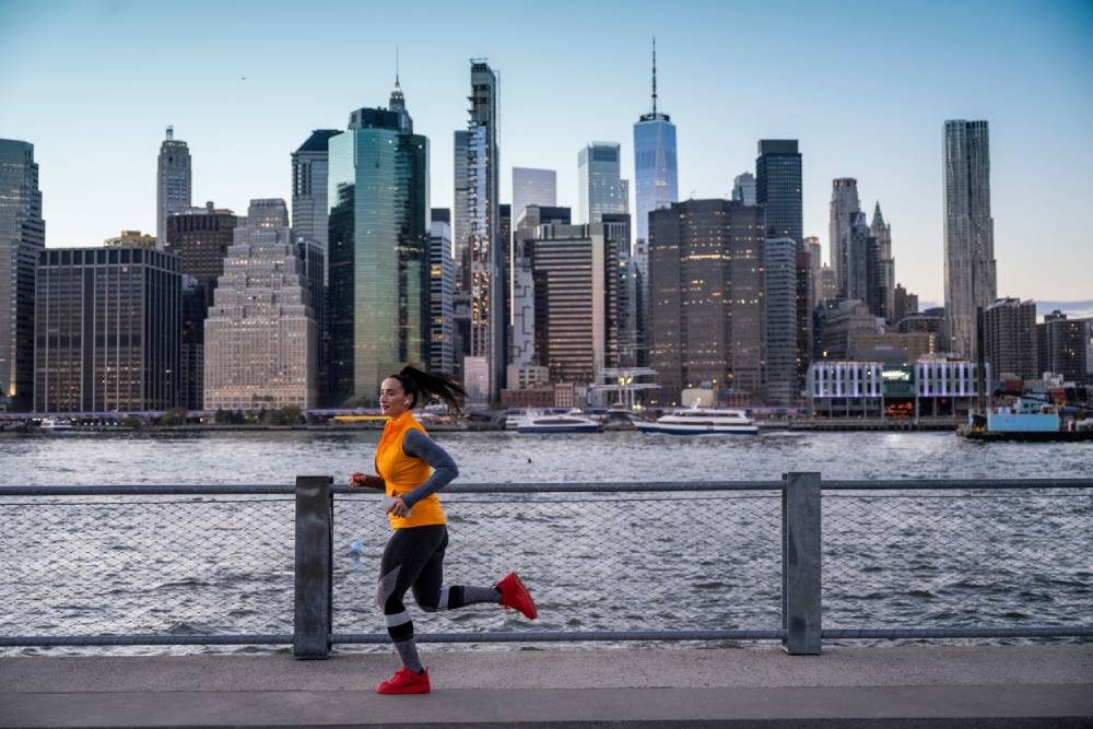 Woman running in Brooklyn with NYC skyline in background